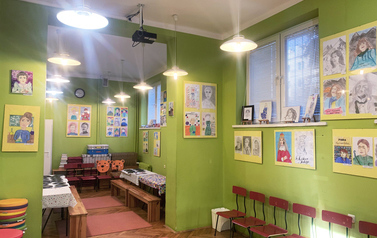 Sala z zielonymi ścianami, na ścianach kolorowe rysunki wykonane przez dzieci