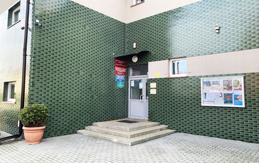 Frontowa ściana budynku z zielonych kafelk&oacute;w z białymi drzwiami wejściowymi
