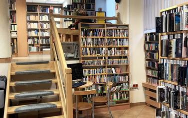 Dwupoziomowe wnętrze biblioteki, na parterze i piętrze regały z książkami