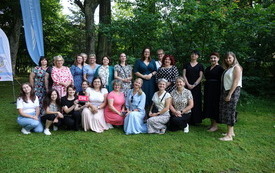 Zdjęcie grupowe 23 kobiet na tle zieleni.