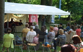 Spotkanie autorskie w parku, w otoczeniu zieleni.