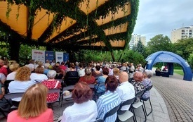 Duża grupa osób na krzesełkach pod amfiteatrem.