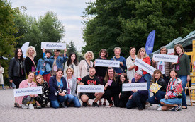 Grupa pracownik&oacute;w biblioteki i goście na zdjęciu grupowym. 