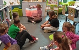 Bibliotekarka prowadzi zajęcia biblioteczne dla dzieci.