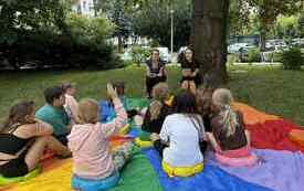 bibliotekarki prowadzą zajęcia dla dzieci na trawie.