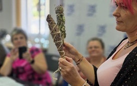 Kobieta trzymająca zwinięte zioła.