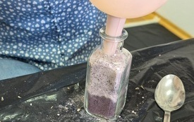 Kobieta przesypuje kolorowy piasek do słoiczka.