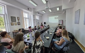 Przy bardzo dużym stole siedzą kobiety w różnym wieku.