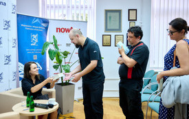 Przy stoliku siedzi kobieta podpisująca książki, obok stoją uczestnicy spotkania