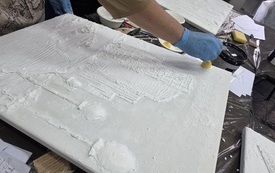 Podobrazie, na którym naniesiono kształt bloku mieszkalnego z gładzi szpachlowej.