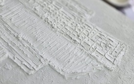 Zbliżenie na obraz przedstawiający blok mieszkalny.