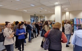 Grupa bibliotekarek w r&oacute;żnym wieku stoi w wypożyczalni pomiędzy regałami