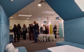 Wnętrze bibliotecznej wypożyczalni dla dzieci, na pierwszym planie pluszowy domek