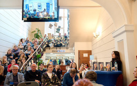 Hol w budynku biblioteki, gdzie siedzą uczestnicy spotkania. 