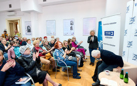 Dyrekcja biblioteki wita gościa, publiczość klaszcze. 