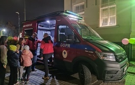 Grupa os&oacute;b stojących przed samochodem GOPR-u