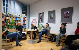 Troje poet&oacute;w i moderator panelu siedzą dyskutując. 