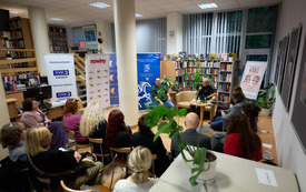 W sali wypożyczalni zgromadzeni uczestnicy panelu poetyckiego. 