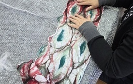 Dłonie tworzące materiał z filcu.