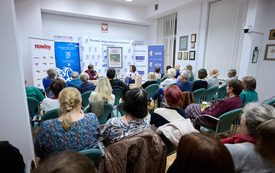 Widownia zebrana w sali bibliotecznej na spotkaniu autorskim. 
