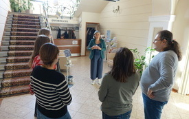 Grupa os&oacute;b stojących w k&oacute;łku w holu biblioteki.