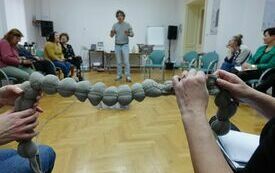 Dwie osoby trzymające w rękach dwa końce sznura w formie kulek z materiału.