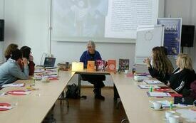 Uczestniczki spotkania patrzące na prowadzącą spotkanie kobietę.