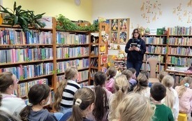 Spotkanie autorskie dla dzieci we wnętrzu biblioteki. 