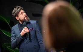 Mężczyzna z mikrofonem patrzy w kierunku ekranu multimedialnego 