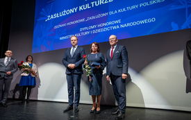 Dw&oacute;ch mężczyzn i kobieta pozują razem do zdjęcia na scenie