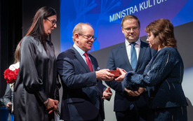 Dw&oacute;ch mężczyzn przekazuje kobiecie prezent w czerwonym pudełeczku 