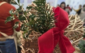 Serce z wikliny ozdobione czerwoną wstążką i zielonymi gałązkami.