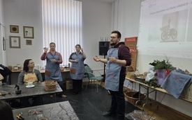 Trzy osoby w fartuchach, obok przy stolikach uczestnicy warsztat&oacute;w