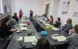 Grupa uczestnik&oacute;w warsztat&oacute;w siedzi przy długim stole