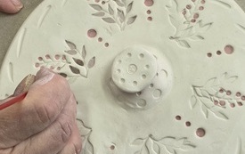 Kobiece ręce dekorujące gliniany talerz
