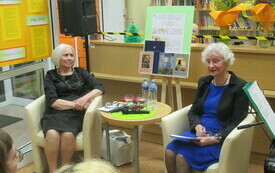 Poetka oraz prowadząca spotkanie siedzą twarzą do widowni.