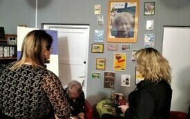 Kobieta rozdająca autografy dw&oacute;m stojącym obok kobietom.