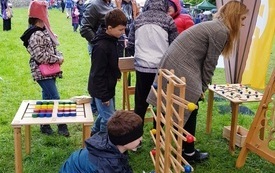 Dorośli oraz dzieci skupieni wok&oacute;ł ustawionych na trawie gier wielkoformatowych. 