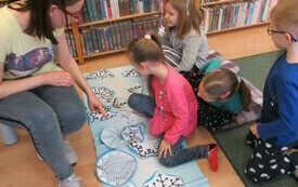 Czworo dzieci bawi się na podłodze w bibliotece