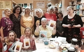 Grupa kobiet w średnim wieku pozuje z książkami w bibliotece