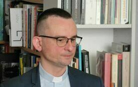 Ksiądz w okularach, koloratce, jasnej koszuli i marynarce