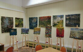 Kolorowe gobeliny wiszą na ścianach oraz leżą na sztalugach