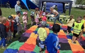 Grupa dzieci podczas zabawy z kolorową chustą. 