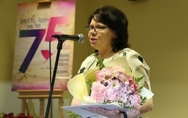 Kobieta z bukietem kwiat&oacute;w przemawia do mikrofonu