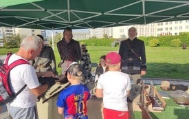Mężczyzna z dziećmi ogląda wystawę broni i mundur&oacute;w z okresu powstania styczniowego