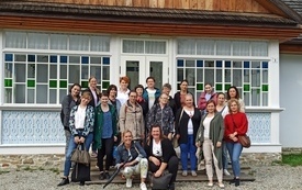 Zdjęcie grupowe uczestniczek warsztat&oacute;w na tle budynku w Skansenie.  