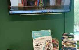 Na stoliku lalki zrobione z kawałów materiałów, książki, laptop.