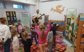 Dzieci tańczą na podłodze do muzyki granej  na gitarze