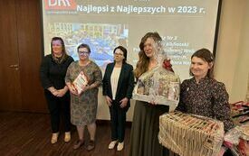 Kilka kobiet stoi obok siebie, dwie trzyamją nagrody zapakowane w folie. W tle napis na ekranie - Najlepsi z Najlepszych DKK  w 2023 r. 