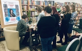 Gość spotkania, kobieta w średnim wieku podczas rozdawania autografów.